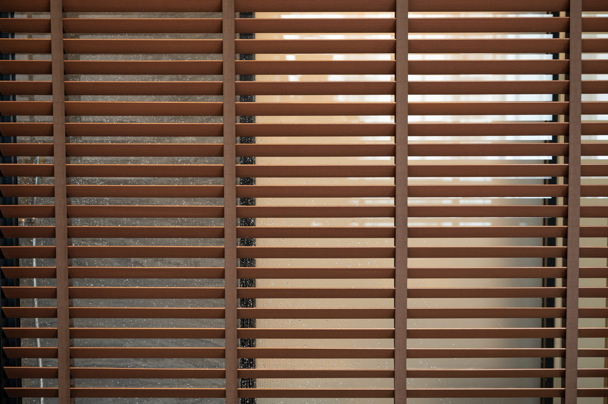 Pattern of brown wooden blinds on glass window